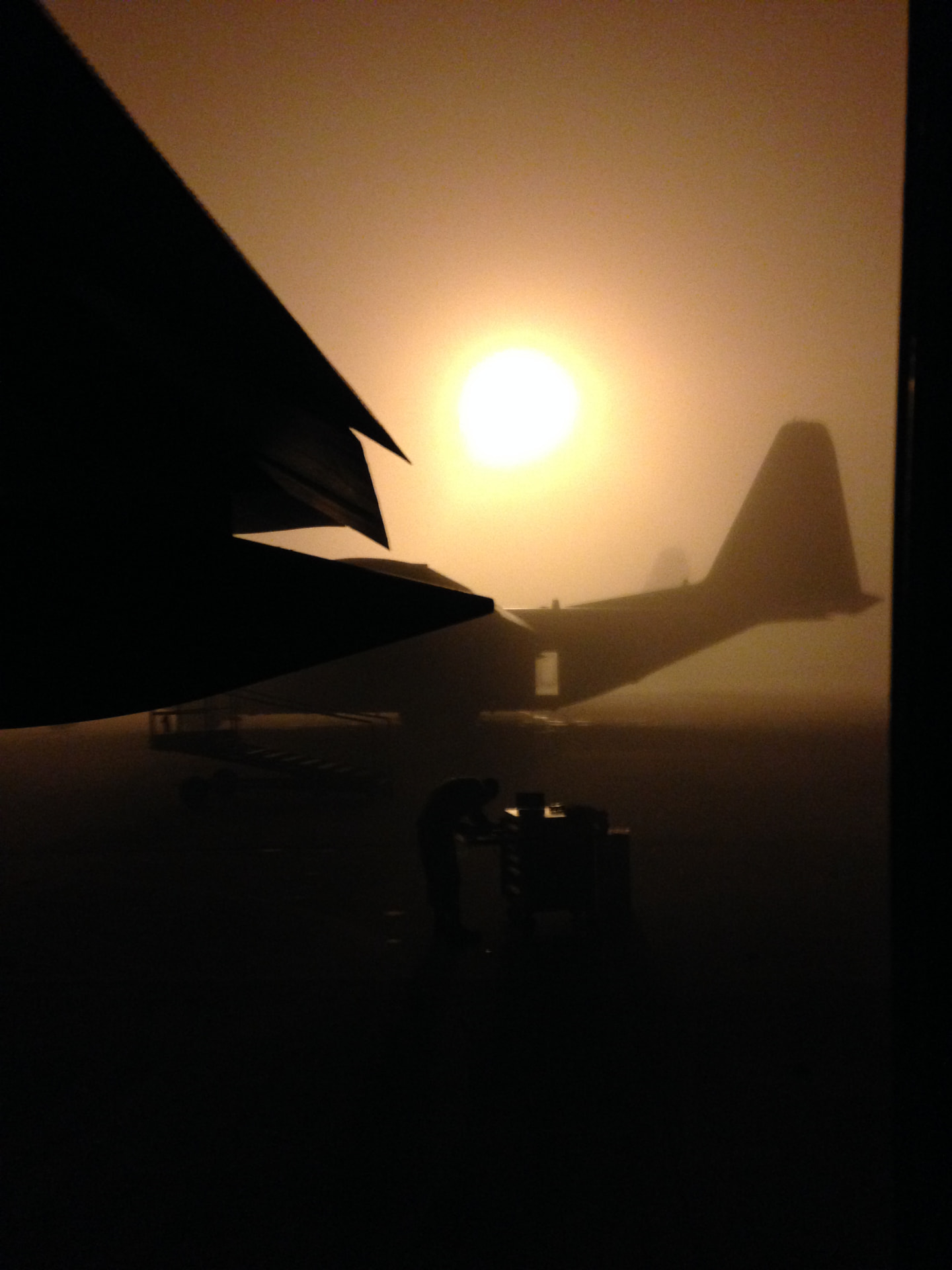 Aircraft silhouettes on a dusty flight line at sunrise